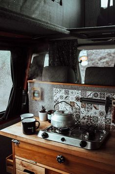 a stove top oven sitting inside of a kitchen next to a wooden cabinet and window