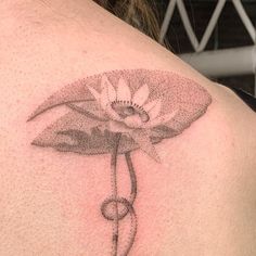 the back of a woman's shoulder with a flower tattoo on her left side