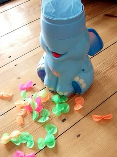 an elephant toy sitting on top of a wooden floor next to confetti pieces