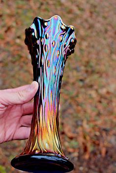 a hand holding a colorful glass vase in the air