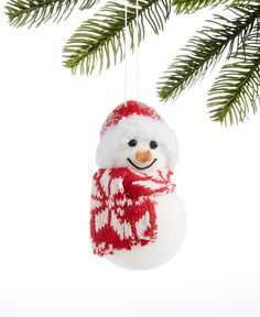 a snowman ornament hanging from a christmas tree with pine branches in the background