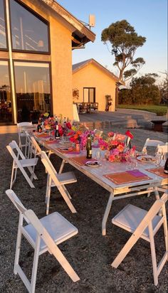 a table set up outside with flowers and wine bottles on it for an outdoor dinner