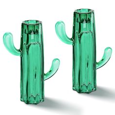 two green glass vases sitting next to each other on a white surface, one with a cactus design