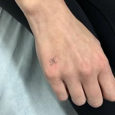 a woman's hand with a small tattoo on her left wrist and the letter k in cursive writing