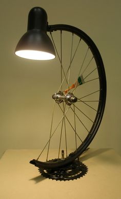 a bicycle wheel with spokes is lit up by a lamp on top of the table