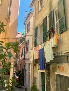 clothes hanging out to dry on a line in an alleyway with buildings and green shutters