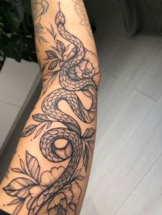 a woman's arm with a snake and flowers tattoo on it