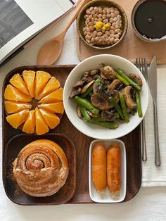 a wooden tray topped with lots of food next to a bowl of beans and carrots