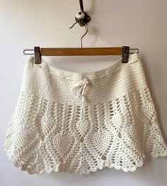 a white crocheted skirt hanging on a wooden hanger