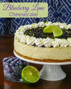 a blueberry lime cheesecake on a cake stand