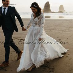 a man and woman are walking on the beach holding hands while dressed in wedding attire