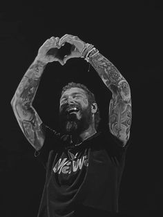 a man with tattoos holding his hands up in the air