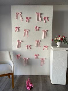 several pieces of pink paper tied to a wall with bows on it and two chairs in the background