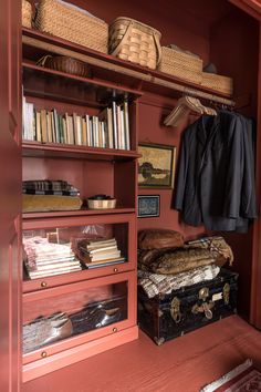 the closet is full of books and other items, including an old trunk with a coat on it