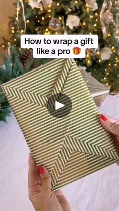 someone is holding up a gift box in front of a christmas tree with the words how to wrap a gift like a pro