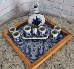 a blue and white tray topped with cups and a tea set on top of a counter