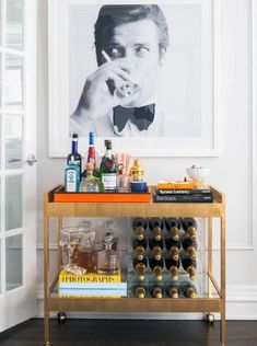 a bar cart with bottles and liquor on it in front of a framed photo,