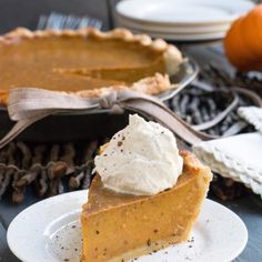 a slice of pumpkin pie on a plate with whipped cream in the middle and an orange behind it