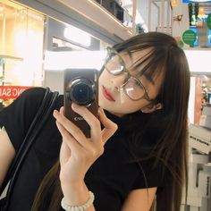 a woman taking a selfie with her cell phone in front of her face and wearing glasses