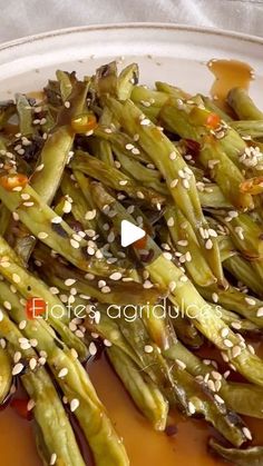 asparagus with sesame seeds and brown sauce on a white plate topped with sesame seeds