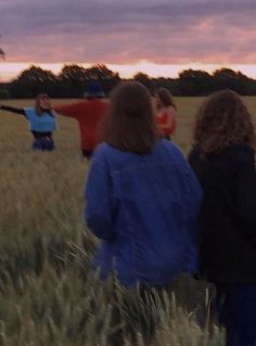 people standing in a field watching the sun set