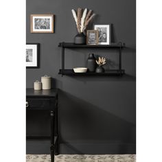 two black shelves with pictures and vases on them against a dark gray painted wall