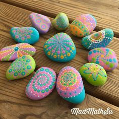 painted rocks are arranged on a wooden surface