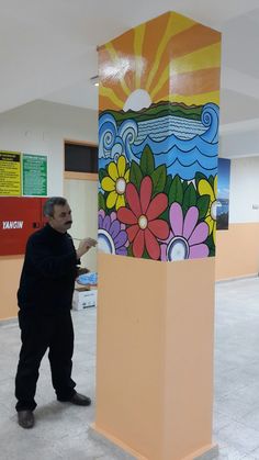 a man standing next to a tall colorful object in an office building with flowers painted on it