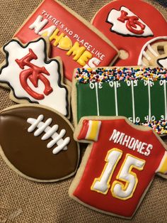 decorated cookies with football, jersey and other sports related items are on a brown surface