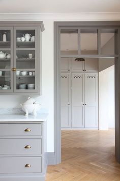 a kitchen with gray cabinets and white counter tops, wood floors, and hardwood flooring