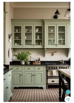 a kitchen with green cupboards and black counter tops, white tile on the floor