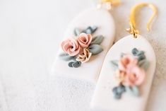 two earrings with flowers on them sitting on a white surface