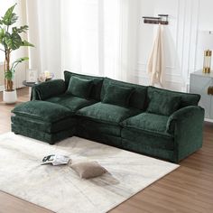 a large green couch sitting on top of a wooden floor next to a white rug