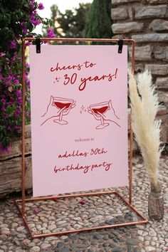 a pink sign that says cheers to 30 years with two glasses in front of it