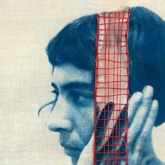 a man is holding his head in front of a painting with red lines on it