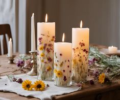 three candles are lit on a table with flowers