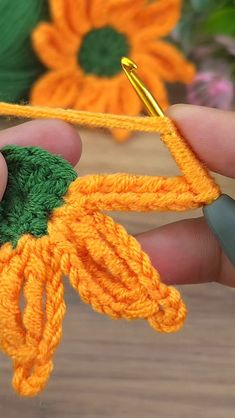 someone is crocheting an orange piece of yarn with a green flower on it