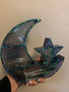 a person holding up a glass sculpture that looks like the moon and stars