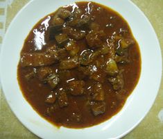 a white plate topped with meat covered in gravy