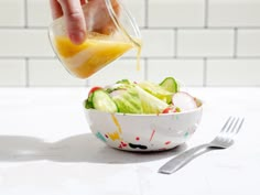 someone is pouring dressing into a bowl of salad