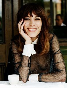 a woman sitting at a table with a cup and saucer in front of her