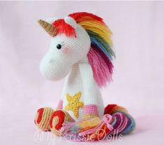 a crocheted unicorn toy sitting on top of a pink surface