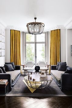 a living room filled with furniture and a chandelier hanging over the top of it