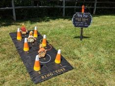 a picnic table set up in the grass with cones and food on it, next to a chalkboard sign that says ring toss