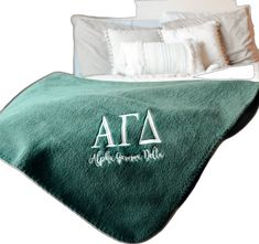 a green blanket with the letters afa on it in front of a white bed