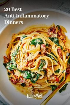 a white plate topped with pasta covered in sauce and spinach next to a fork