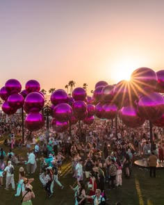 a large group of people standing on top of a lush green field next to palm trees