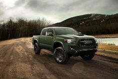 a green truck driving down a dirt road