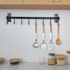 kitchen utensils hanging on the wall with wooden spoons and spatulas