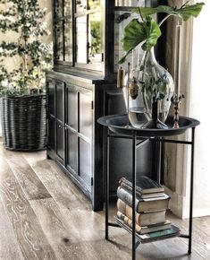 a table with some books and a plant on it in front of a window sill